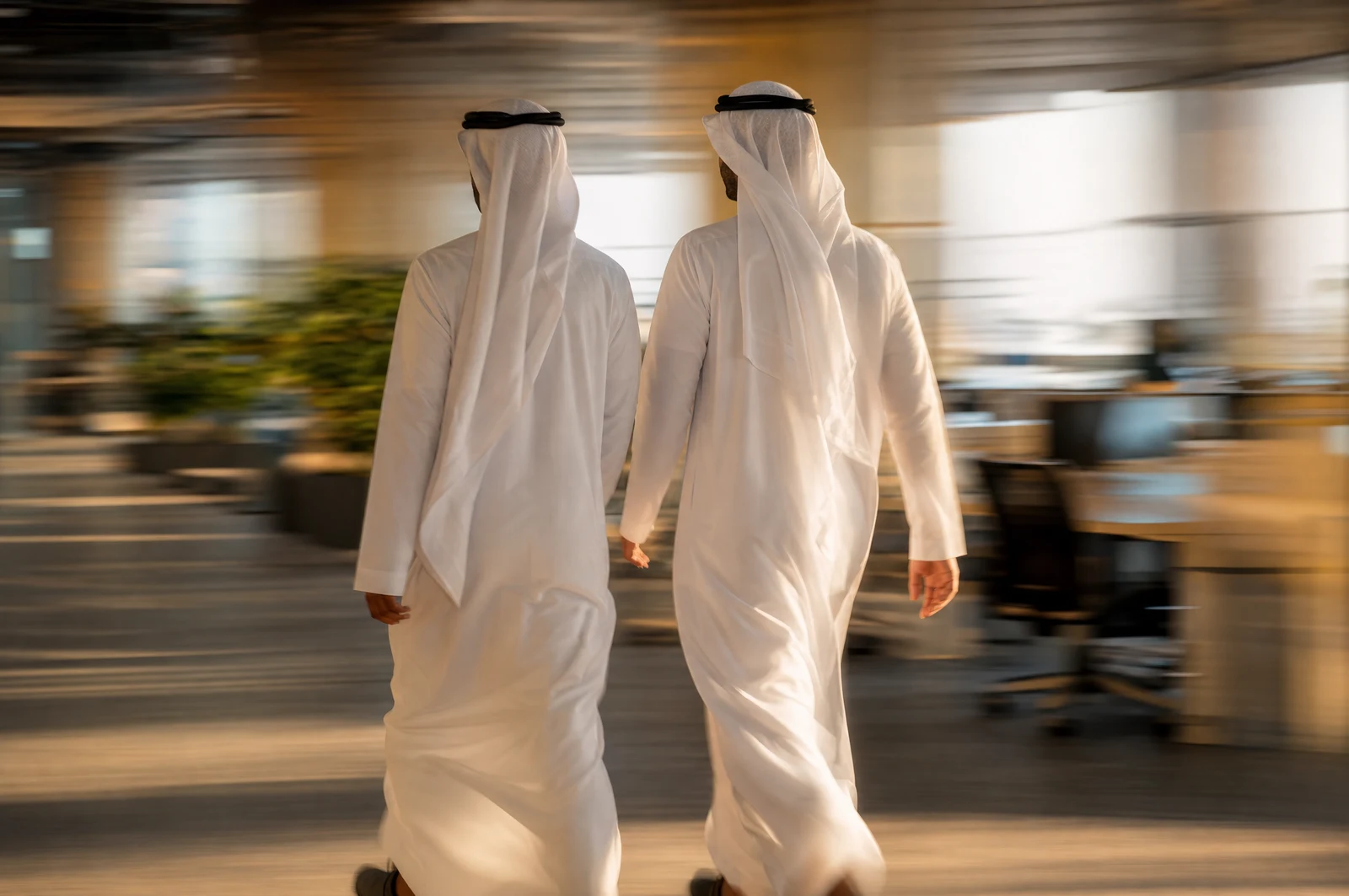 رجال أعمال سعوديون يمشون في مكتب حديث في ضوء الغروب